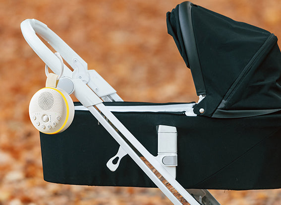 Black stroller with a swiftvein nimbus device attached to the handle against a blurred natural background