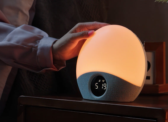 Person holding a glowing night light with a digital display in a dimly lit room.