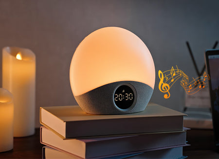 Round night light with digital clock on books, candles in the background